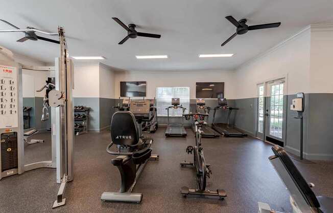 A gym with a variety of equipment including treadmills, stationary bikes, and weight machines.