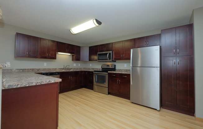 a kitchen with wooden cabinets and a stainless steel refrigerator. Fargo, ND Urban Plains Apartments