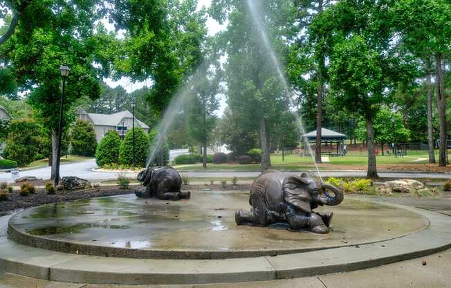 three elephants sit in a fountain in a park