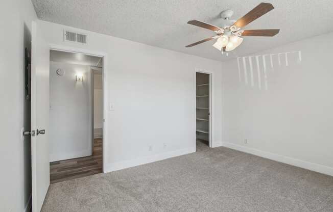 A room with a ceiling fan and carpeted floor.