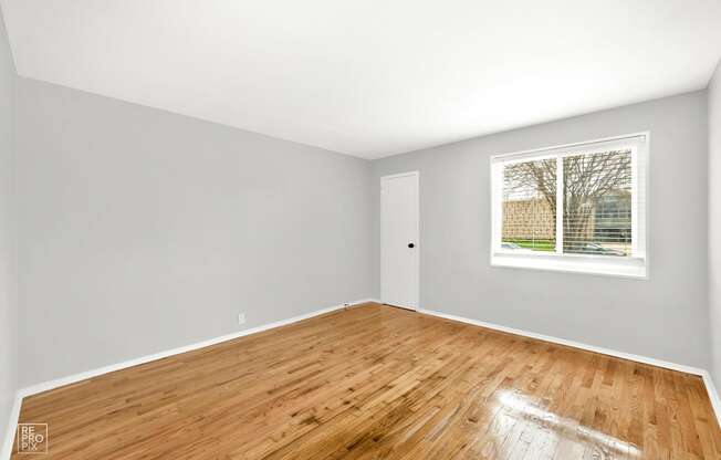 a bedroom with hardwood floors and a large window