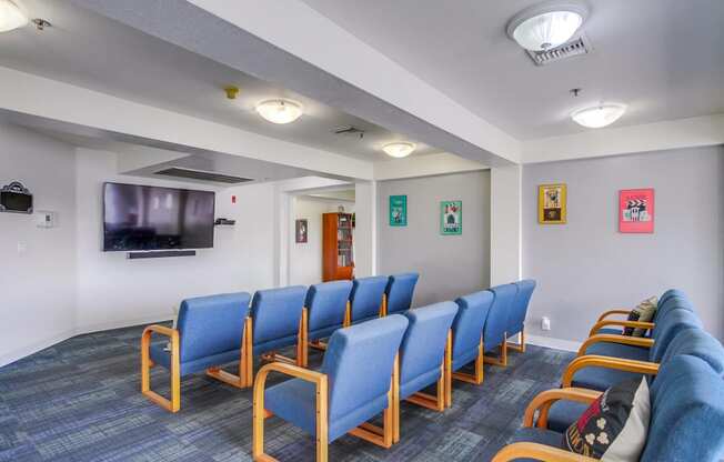 a waiting room with blue chairs and a tv