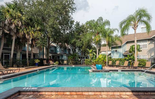 a swimming pool with palm trees in front of apartment buildings