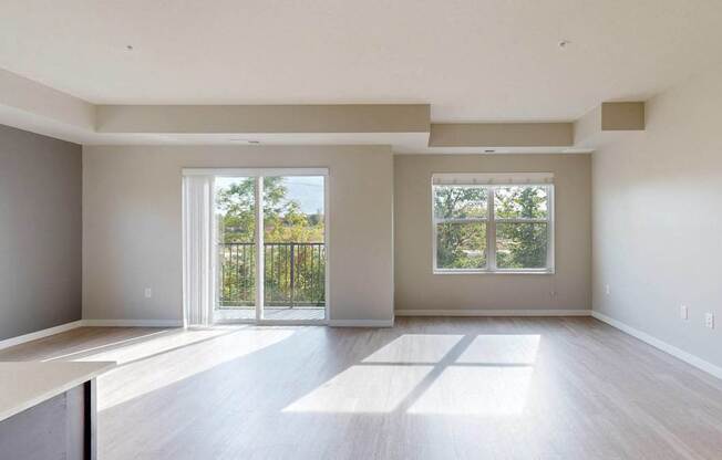 A large, empty room with a sliding glass door leading to a balcony.