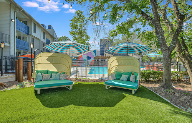 two lounge chairs with umbrellas in front of a pool