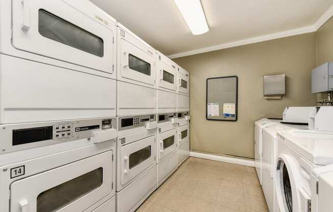 The Woods community laundry room with many washers and dryers in shared access room.