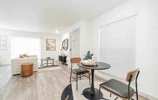 A living room with a white sofa, a black table, and a wooden chair.