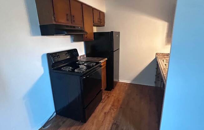A modern kitchen with a wooden wall and black appliances.