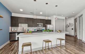 A kitchen with a white counter and bar stools.