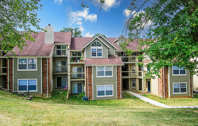 an exterior view of an apartment building with grass and trees