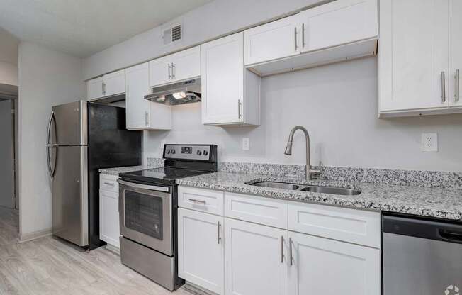 A kitchen with white cabinets and a granite countertop.