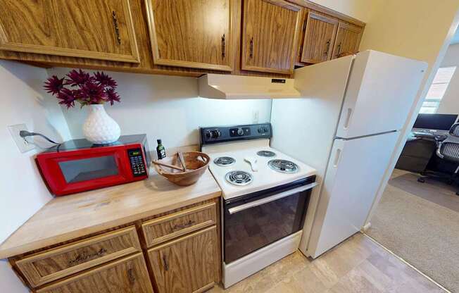 A kitchen with wooden cabinets and a red microwave.