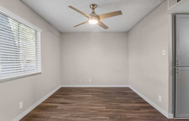 an empty room with a ceiling fan and a window