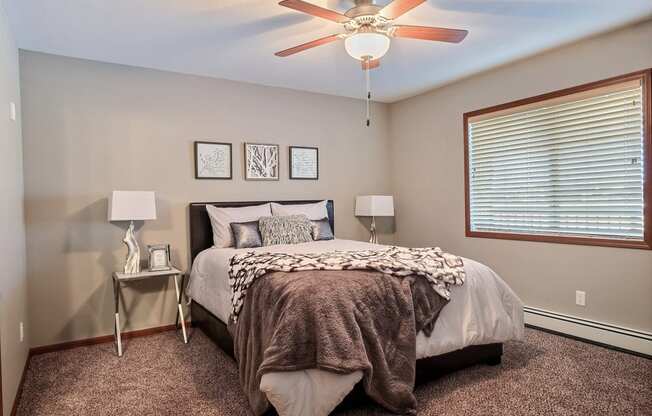 a bedroom with a large bed and a ceiling fan. Fargo, ND Urban Plains Apartments