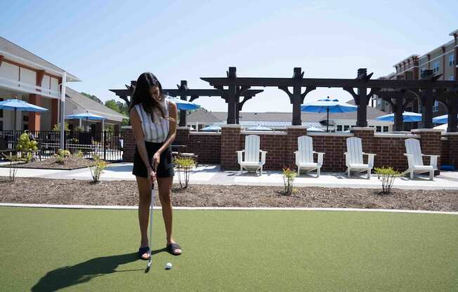 A woman is playing mini golf on a sunny day.