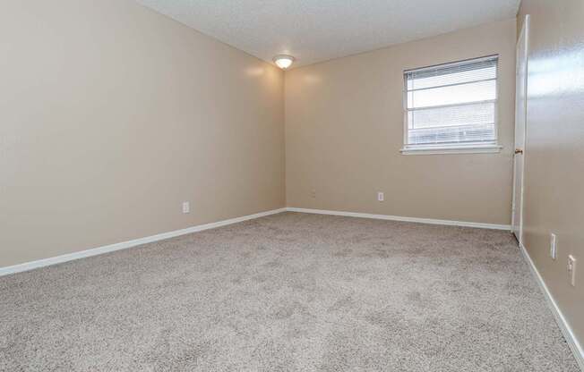 A bedroom with a carpeted floor and a window  at The Creole Apartments in Shreveport, LA