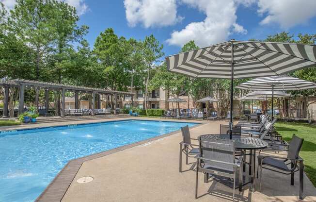 Apartments In Houston Texas for Rent – Westchase Forest - Photo of a swimming pool with tables and umbrellas next to it