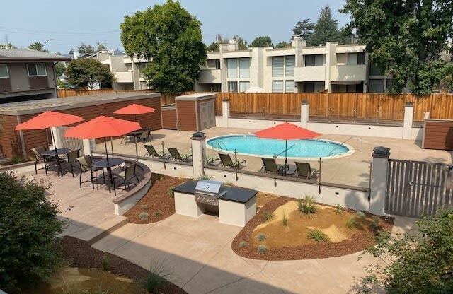 a pool and tables with umbrellas in an apartment yard