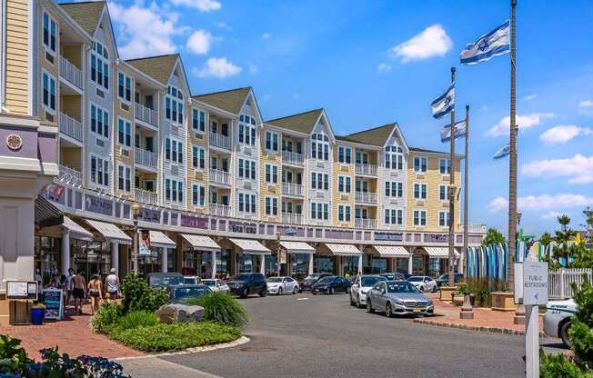 A sunny day at a bustling shopping center with cars parked and people walking.