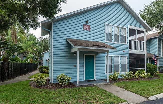 the front of a blue house with a green door