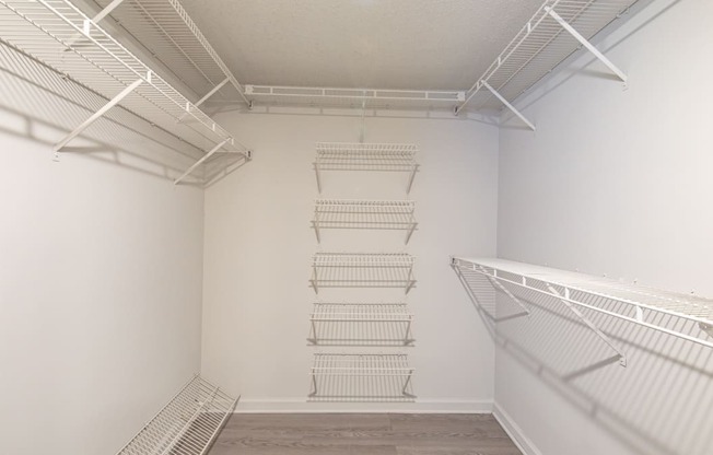 a room with white walls and a white closet with metal shelves