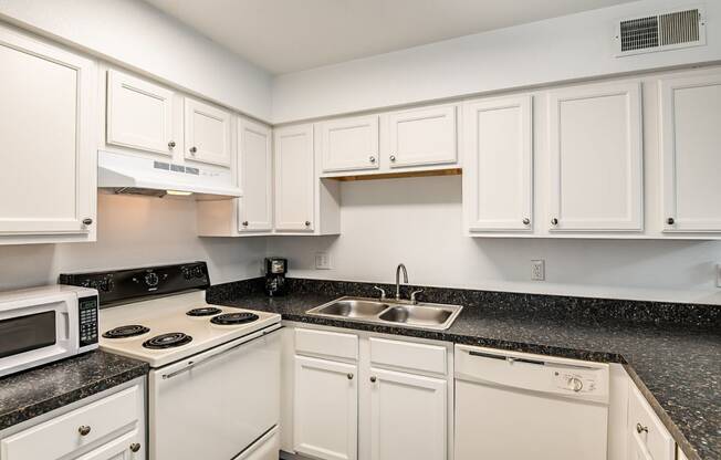 a kitchen with white cabinets and granite counter tops and a sink