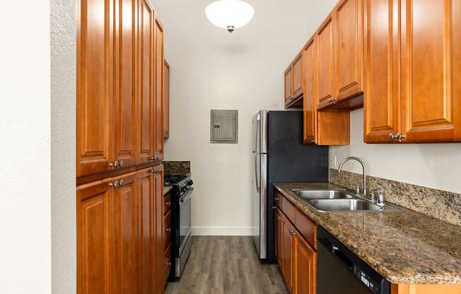 A kitchen with wooden cabinets and a black refrigerator.