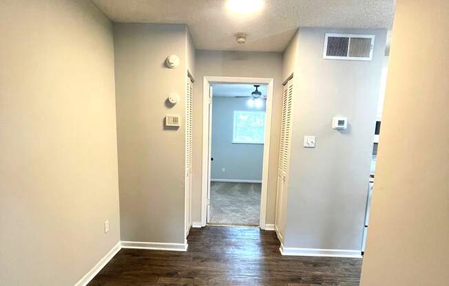 A long, narrow hallway with wood flooring and white walls.