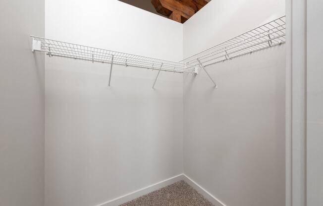 a spacious walk in closet in a bedroom with white walls and a ceiling with shelves