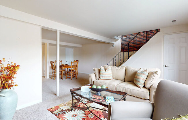 A living room with a couch, coffee table, and a staircase.