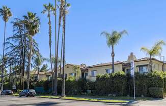 A row of palm trees in front of a house.