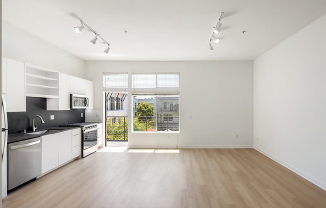 A kitchen with white cabinets and a window overlooking a street.