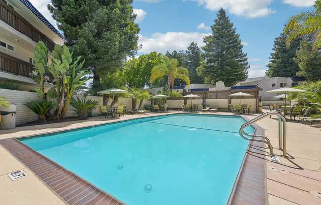 a swimming pool with trees and a building in the background