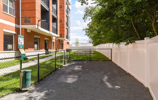 a fenced in area with a tennis court in front of a building