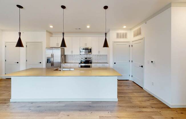 A kitchen with a white island and pendant lights.