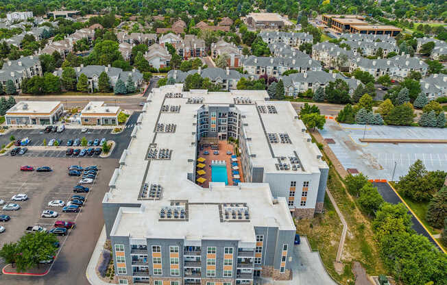 an aerial view of a large apartment complex with trees in the background