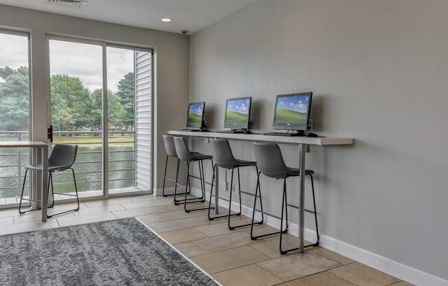 a room with a bar with three computers on it and a glass door