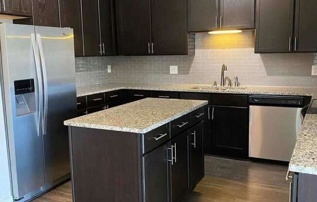 Modern kitchen with backsplash and island at Flats on 4th Apartments in Birmingham, AL