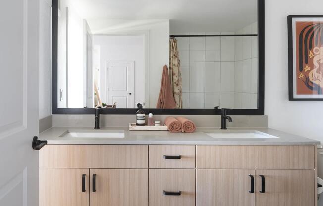 A spacious double vanity with light wood cabinetry, matte black accents, and generous counter space for an elevated daily routine.