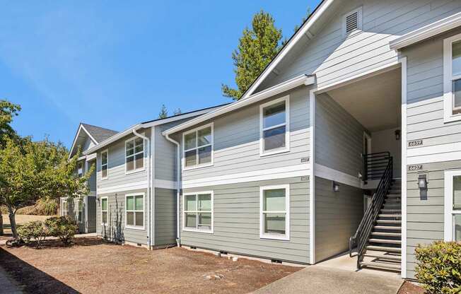 A grey two story apartment building with a staircase leading to the second floor.