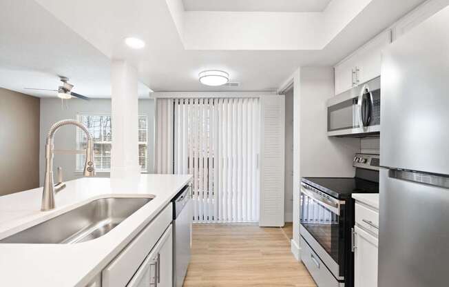 A modern kitchen with stainless steel appliances and white countertops.