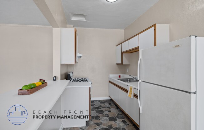 A kitchen with a refrigerator, sink, stove and cabinets.