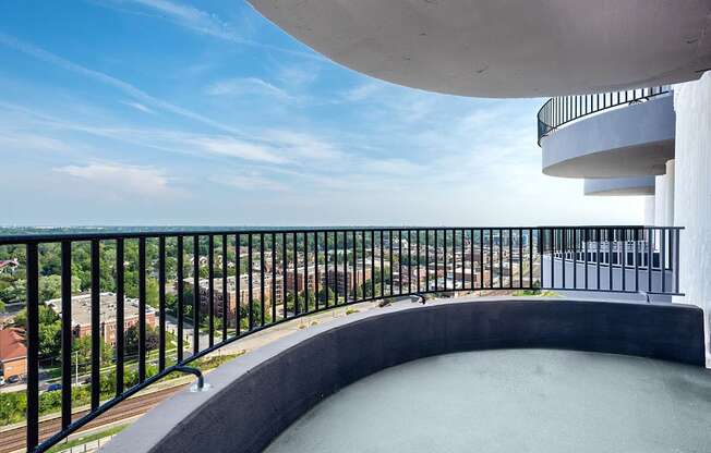 A balcony with a black railing overlooks a cityscape.