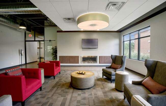 A modern lounge area with red couches and a fireplace.