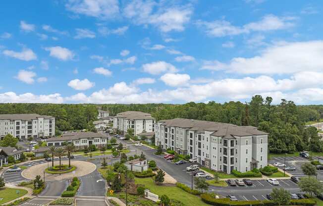 an aerial view of an apartment complex with parking lot and trees