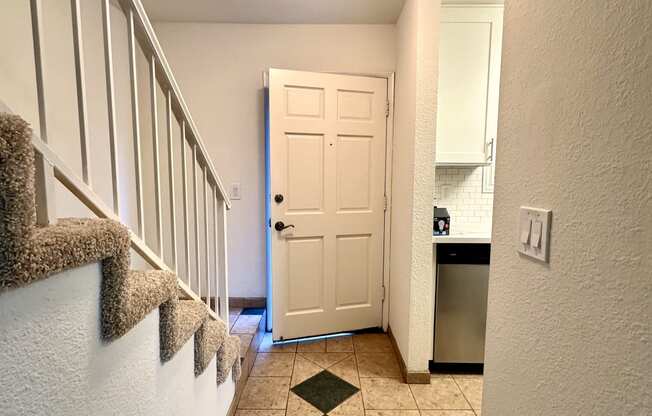 a hallway with stairs and a door to a kitchen