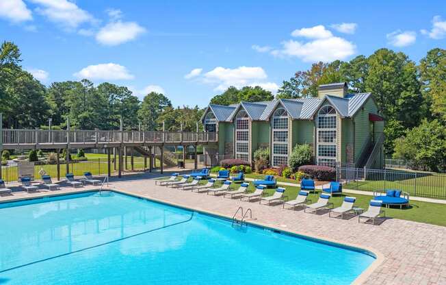 a resort style pool with lounge chairs and a building in the background