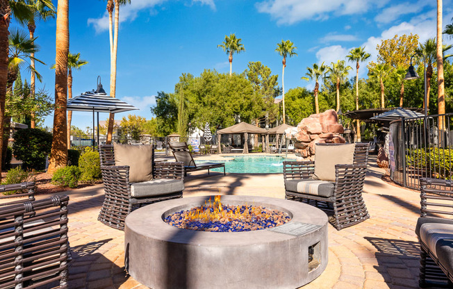 an outdoor patio with a fire pit and chairs and a pool