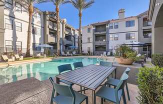 A table and chairs are set up on a patio next to a pool.