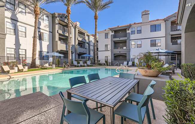 A table and chairs are set up on a patio next to a pool.